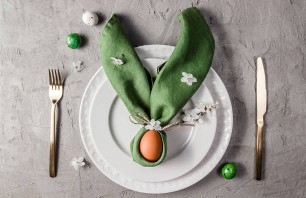 istock Easter table setting. Empty plates with green linen napkin and golden cutlery on concrete background. Top view. Flat lay. Copy space. 1216224628