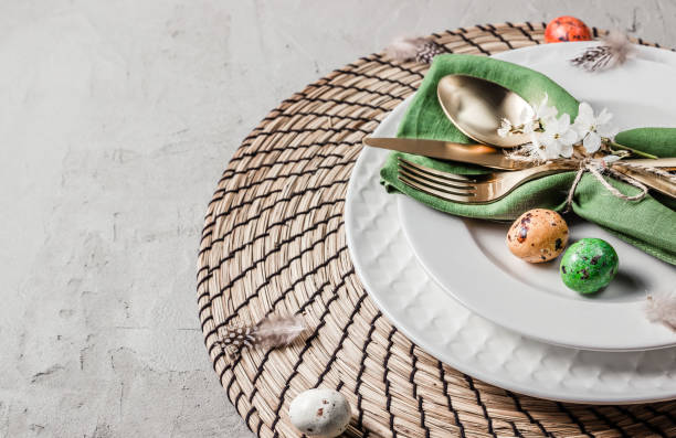 Easter table setting. Empty plates with green linen napkin and golden cutlery on concrete background. Top view. Flat lay. Copy space.