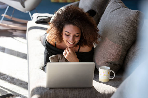 Young woman lies on a couch with laptop computer