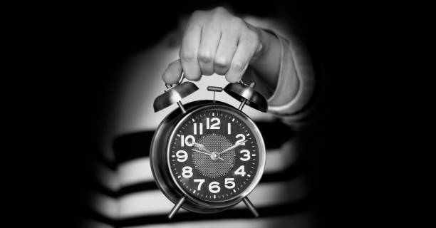 femme de plan rapproché noir et blanc retenant le réveil affichant dix heures - clock face alarm clock clock minute hand photos et images de collection