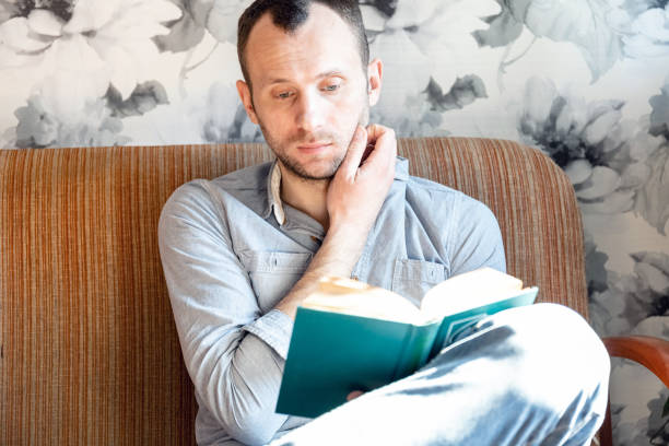 istock young man reading a book while sitting on a sofa in an apartment 1216229847