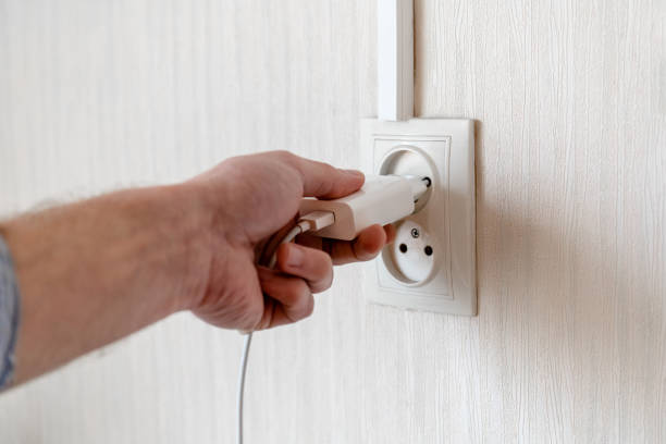 istock man's hand plugs into a power outlet 1216229867