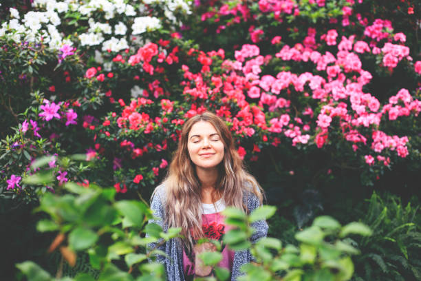 Young happy girl with eyes closed enjoying the nature and flowers