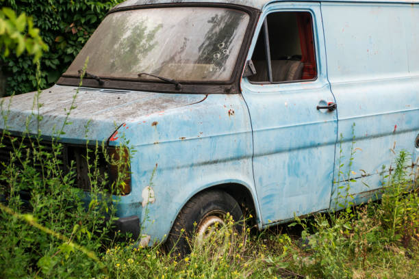 altes verlassenes auto, rostiges auto. ein verlassenes antikes auto, mit verblasster blauer farbe. das alte verlassene auto war mit vegetation bewachsen. - house car burnt accident stock-fotos und bilder