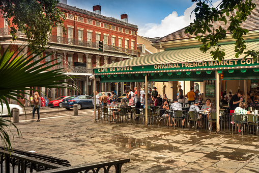 New Orleans, Louisiana - June 17, 2019:  People gather in front of the historic Cafe Du Monde market in the French quarter of New Orleans Louisiana USA.  The cafe is known for café au laits, chicory coffee & beignets since 1862.