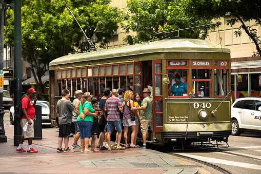 New Orleans, Louisiana - June 17, 2019:  People board the historic streetcar along Saint Charles Avenue in the Garden District of New Orleans Louisiana USA.  The St. Charles Avenue line is the oldest continuously operating street rail system in the world.