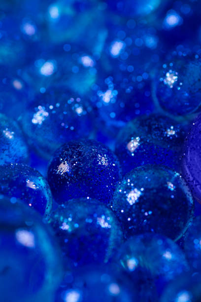 istock Closeup blue transparent balls sprinkled with sequins with selective focus. Abstract textured background with copy space 1216234476