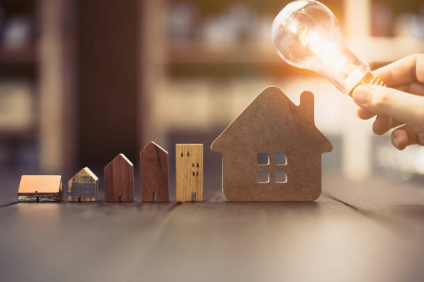 Light bulb with wood house on the table, a symbol for construction, Creative light bulb idea, power energy or business idea concept ecology, loan, mortgage, property or home.
