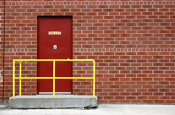 Red fire exit door on the side of a red brick wall