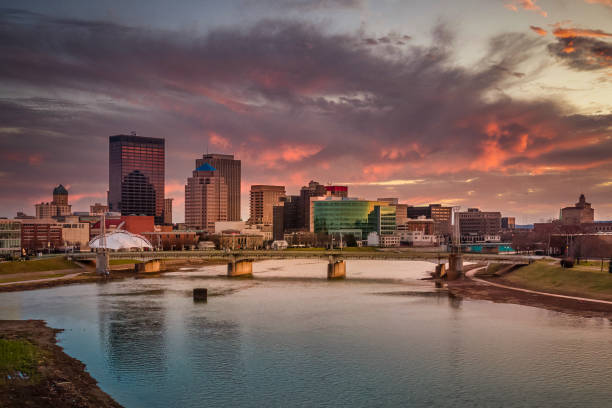 Urban Pink The skyline of downtown Dayton, Ohio under a sunset of pink clouds from the Great Miami River taken from a drone for an aerial view. dayton ohio skyline stock pictures, royalty-free photos & images