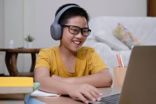 Asian boy enjoy self study with e-learning at home. Cheerfully boy excited using computer online learning schoolwork. Asian boy enjoy self study with e-learning at home. Online education and self study and homeschooling concept. home schooling homework computer learning stock pictures, royalty-free photos & images