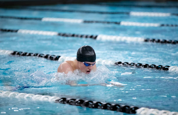 junge männliche schwimmerin schwimmt den brustschlag während eines wettkampfes - breaststroke stock-fotos und bilder