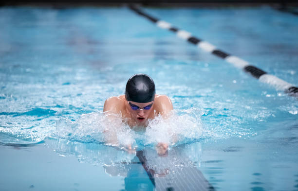 junge männliche schwimmerin schwimmt den brustschlag während eines wettkampfes - breaststroke stock-fotos und bilder