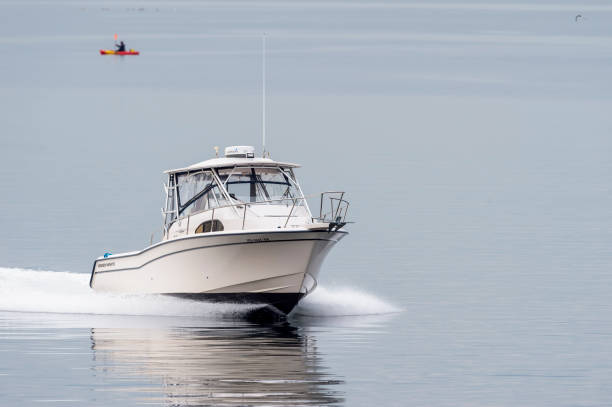 Powerboat cruising across flat water Fairhaven, Massachusetts, USA - May 1, 2019: Powerboat cruising across flat water in foggy New Bedford outer harbor racing boat photos stock pictures, royalty-free photos & images