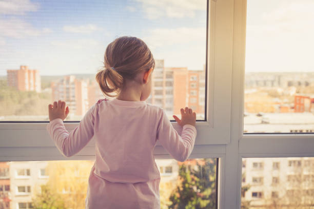 View through window of a serious little boy sitting on the back seat of the car