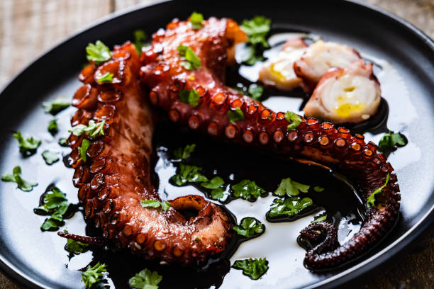 обжаренный осьминог на деревянном столе - prepared fish seafood barbecue grilled стоковые фото и изображения