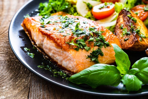 istock Fried salmon, fried potatoes and vegetables on wooden background 1216252291
