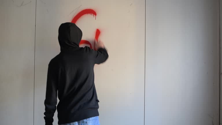 guy inscribes spray paint on a clean wall in an abandoned building