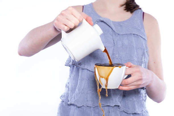 A lovely young blonde woman pouring coffee smiles up at the camera.