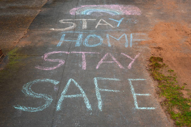 Rainbow and Stay Home Stay Safe chalk drawings on pavement during Covid19 in UK. Rainbow and Stay Home Stay Safe chalk drawings on pavement during Covid19 in UK. stay at home order stock pictures, royalty-free photos & images
