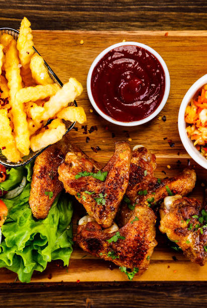 istock Barbecue chicken wings and vegetables on wooden board 1216255381