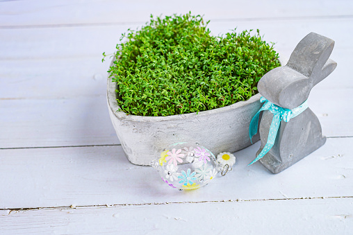 concrete bunny and easter egg next to a flower pot with green leaves in the shape of a heart