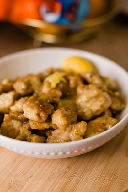 istock A Shallow Bowl with Chinese Lemon Chicken Sitting on a Wood Table 1216256925