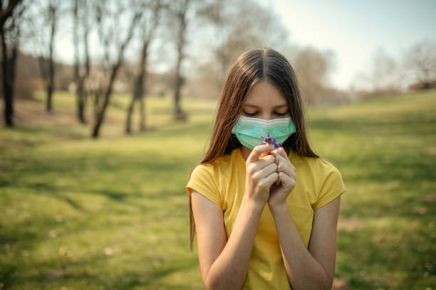istock Girl wears protective mask outdoors and smelling flowers 1216259103
