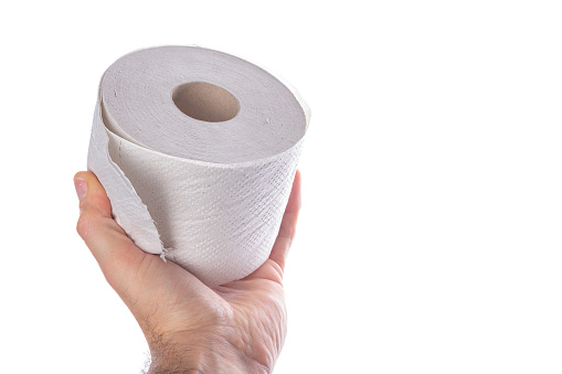 Toilet paper in hand. Male hand with a roll of toilet paper. Light background.