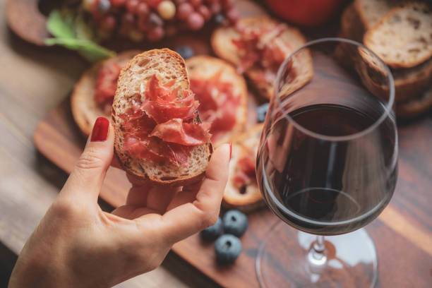 Glasses of red wine  on wooden board Selective foucs on finger holding ham jamon serrano and glasses of red wine  on wooden board tapas stock pictures, royalty-free photos & images