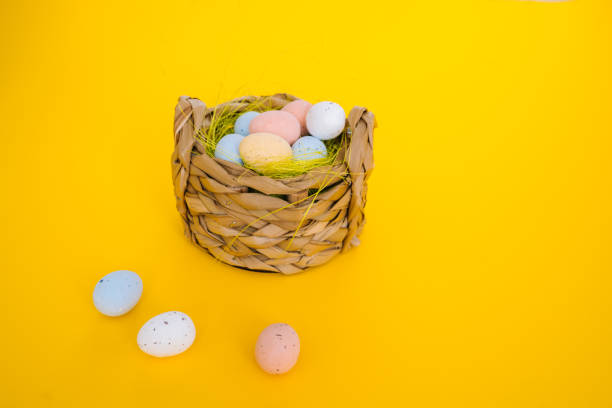istock Easter holiday decorations on yellow background. Colorful easter painted speckled eggs in basket. Creative spring composition with Easter elements - flowers and eggs. Traditional Easter Celebrating 1216260878