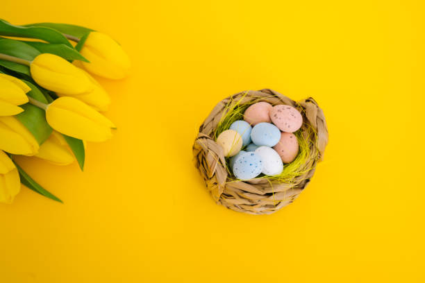 istock Easter holiday decorations on yellow background. Colorful easter painted speckled eggs in basket. Creative spring composition with Easter elements - flowers and eggs. Traditional Easter Celebrating 1216261916