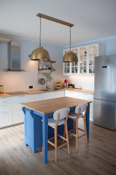 White kitchen with blue island and wooden floor. Vertical shot. stock photo