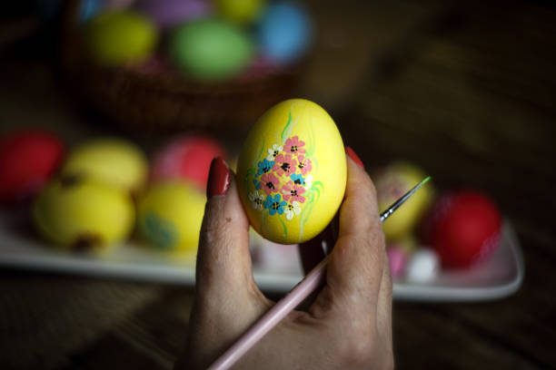istock Woman hands is holding eggs with floral patterns. Preparing for Easter. Artist paints an Easter egg. Close-up. Selective focus. Copy space. Horizontal orientation. 1216262382