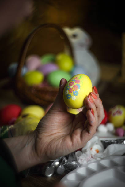 Woman hands is holding eggs with floral patterns. Preparing for Easter. Artist paints an Easter egg. Close-up. Selective focus. Copy space. Vertical orientation.
