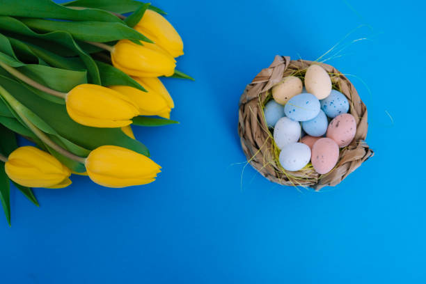 istock Happy Easter. Easter holiday decorations on trendy colored classic blue background. Creative spring composition with Easter elements - flowers and eggs in basket. Celebrating Easter concept at spring 1216266183