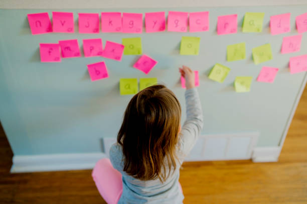 istock Child Arranging Sticky Note Letters to Practice Spelling 1216267236