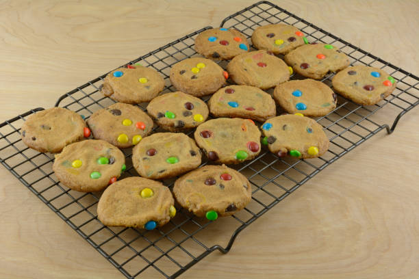 Batch of candy covered chocolate piece cookies fresh out of the oven on cooling rack
