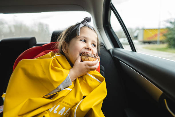 istock Cute girl enjoying a donut while on a road trip 1216271443