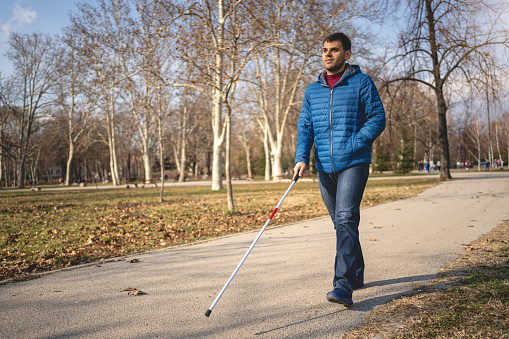 Young blind man enjoying a walk in a public park