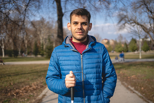 Young blind man standing in a public park portrait