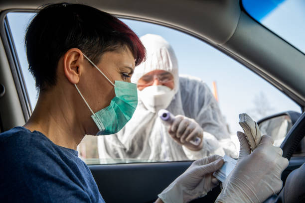 istock Female driver at road control for COVID-19 testing reaching for ID document 1216272541