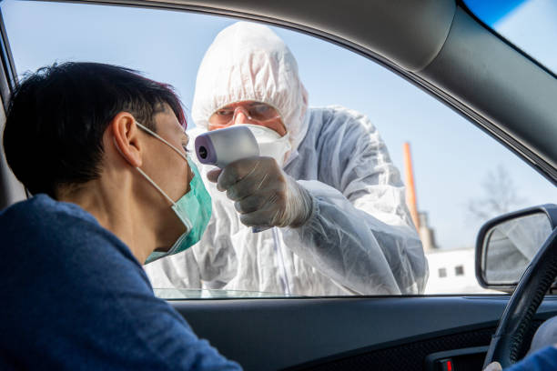 Female driver exposing her forehead for the COVID-19 body temperature testing Female driver exposing her forehead for the COVID-19 body temperature testing driver occupation photos stock pictures, royalty-free photos & images