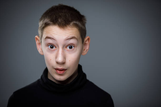 Portrait of a teenager in front of a blue terrace wall in summer. He looks thoughtfully.