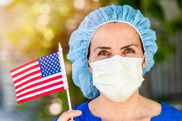 grave lavoratrice che ha un'assistenza sanitaria matura e troppo al lavoro con in mano una bandiera statunitense - depression sadness usa american flag foto e immagini stock