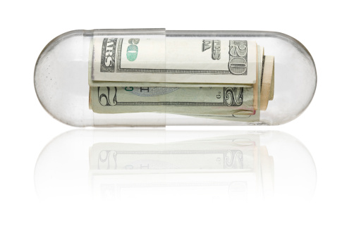 Dollar bills in medicine capsule - healthcare costs concept