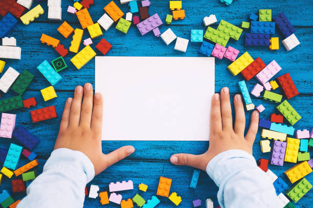 istock Colored toy bricks and blank card with child hands. School or preschool background. 1216286375
