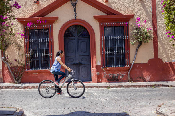 Beautiful young woman with bicycle and flowers on street
