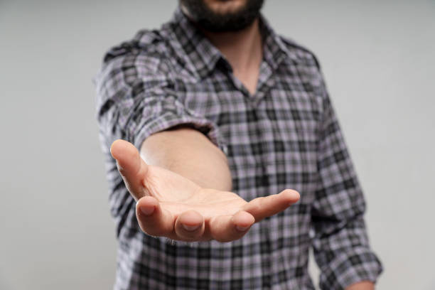 The man is standing and shows an outstretched hand with an open palm. Businessman showing empty hand and presenting with hand empty copy space. Open hand, Holding, giving, showing, presenting concept.