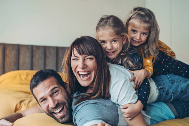 moeder, vader en tweelingmeisjes die bovenop elkaar worden gestapeld - bed fotos stockfoto's en -beelden